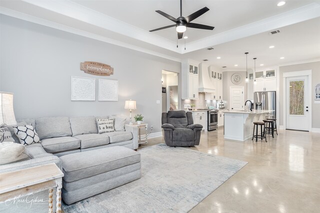 living area with a large fireplace, baseboards, a tray ceiling, and crown molding