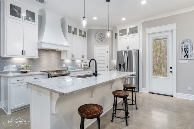 kitchen with custom exhaust hood, stainless steel appliances, tasteful backsplash, a sink, and a kitchen breakfast bar