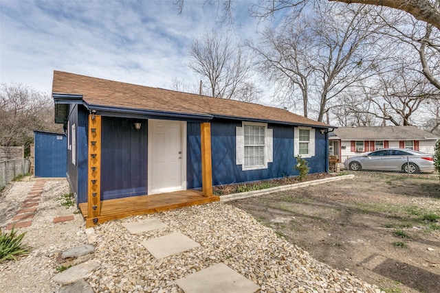 view of front of home with a shingled roof and fence