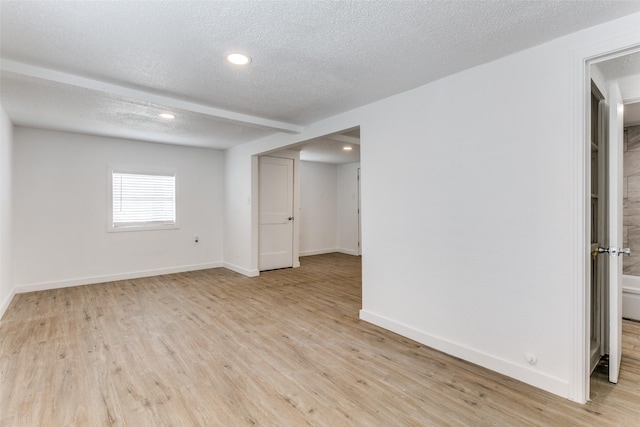 spare room featuring light wood-type flooring, baseboards, a textured ceiling, and recessed lighting