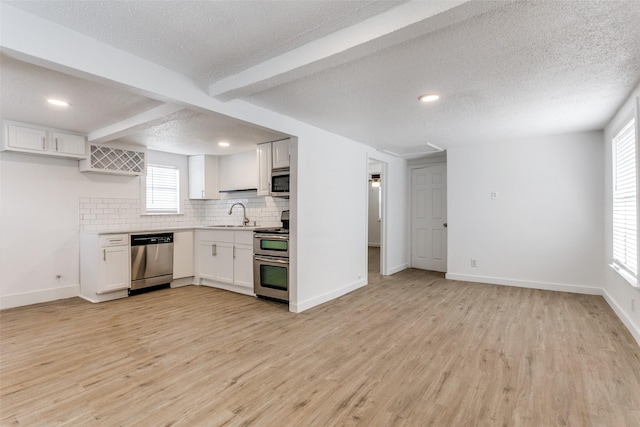 kitchen featuring light wood-type flooring, beam ceiling, stainless steel appliances, and a sink