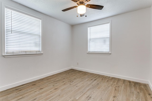 spare room with light wood-style floors, a textured ceiling, baseboards, and a ceiling fan