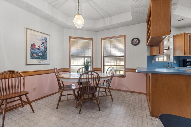 103 Holly Hill Ln, Bullard, TX 75757 - dining area featuring wainscoting, a raised ceiling, light floors, and a textured ceiling