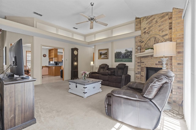 living room with ceiling fan, a brick fireplace, visible vents, and light colored carpet