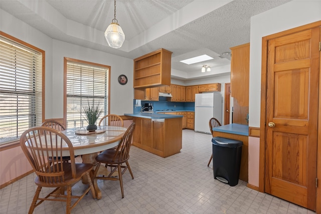 dining area with a tray ceiling, a textured ceiling, and a skylight