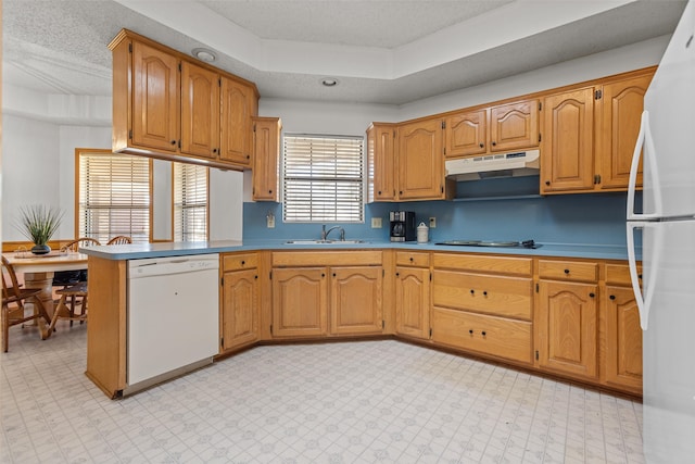 kitchen featuring white appliances, light floors, a peninsula, under cabinet range hood, and a sink