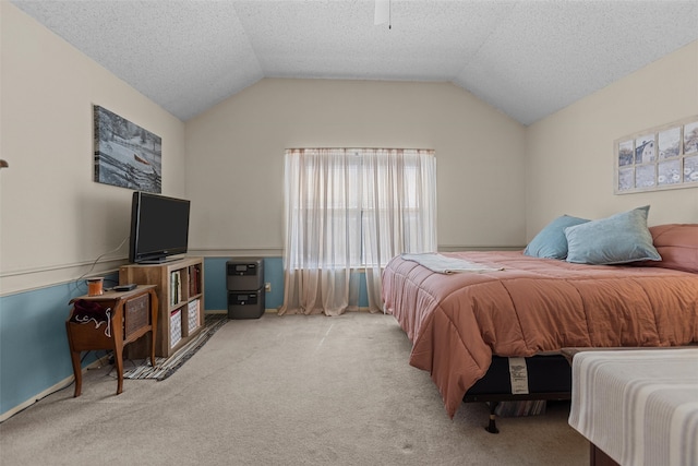 carpeted bedroom with vaulted ceiling, a textured ceiling, and ceiling fan