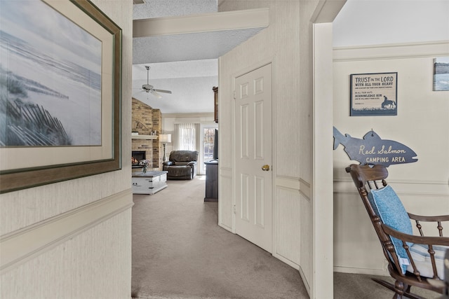 hallway featuring carpet floors, vaulted ceiling, and a textured ceiling