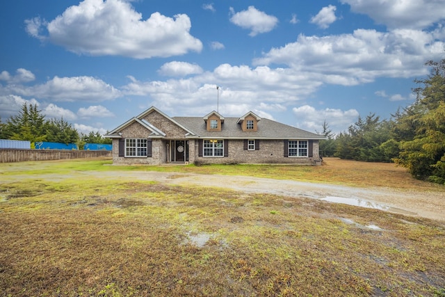 view of front of property with brick siding, a front lawn, and fence