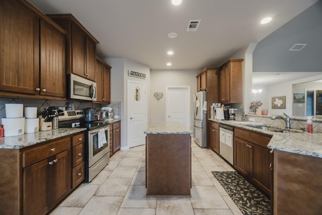 kitchen with visible vents, a kitchen island, a sink, stainless steel appliances, and tasteful backsplash