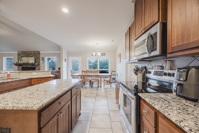 kitchen featuring brown cabinetry, light tile patterned floors, stainless steel appliances, and a sink