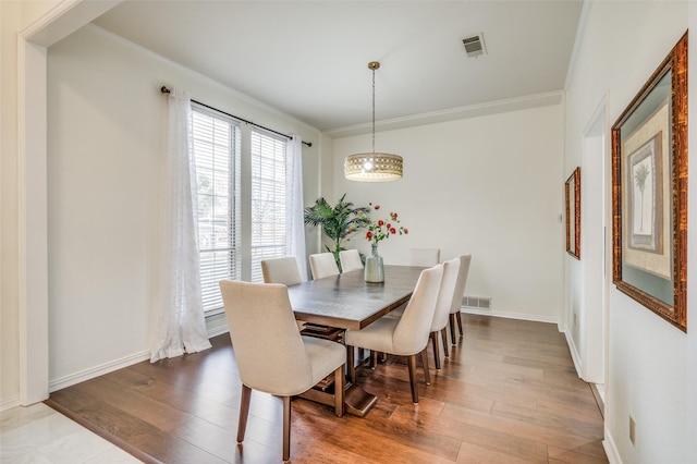 dining area with crown molding, wood finished floors, visible vents, and baseboards