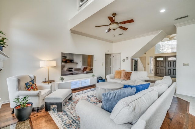 living room featuring a high ceiling, visible vents, wood finished floors, and ornamental molding