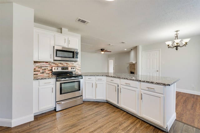 kitchen featuring light wood-style flooring, stainless steel appliances, a peninsula, visible vents, and white cabinets