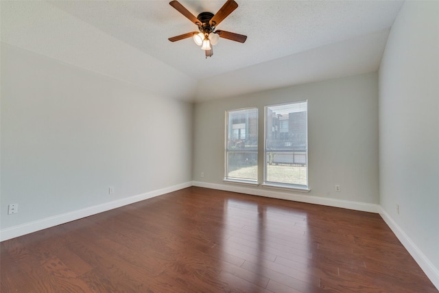 empty room featuring dark wood-style floors, ceiling fan, baseboards, and vaulted ceiling