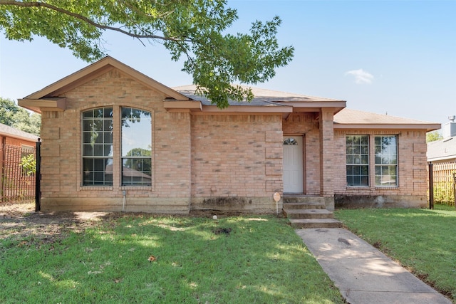 ranch-style home featuring brick siding, a front yard, and fence