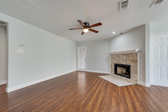 unfurnished living room featuring baseboards, visible vents, dark wood finished floors, and a tiled fireplace