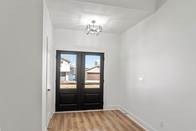 foyer featuring french doors, baseboards, an inviting chandelier, and light wood finished floors