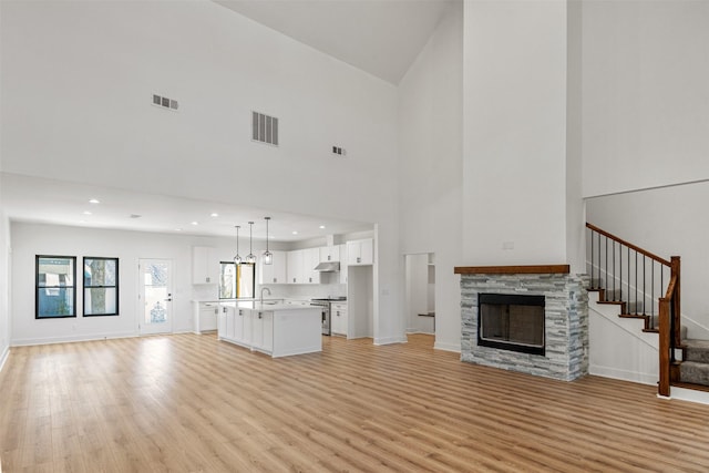 unfurnished living room featuring stairs, light wood-style floors, and visible vents