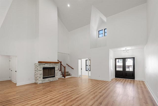 foyer featuring stairway, a stone fireplace, light wood-type flooring, and baseboards