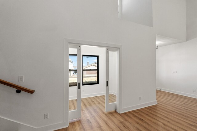 interior space featuring light wood finished floors, a high ceiling, and baseboards