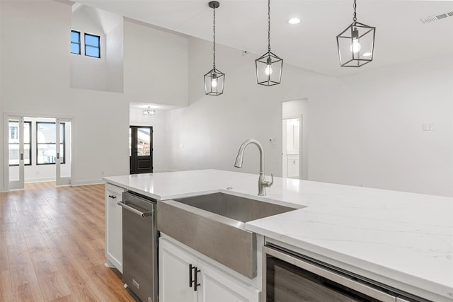 kitchen with hanging light fixtures, visible vents, light wood-style flooring, and a sink