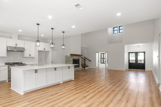 kitchen featuring visible vents, under cabinet range hood, open floor plan, light countertops, and high end stainless steel range oven