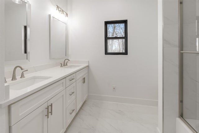 full bathroom with double vanity, marble finish floor, baseboards, and a sink