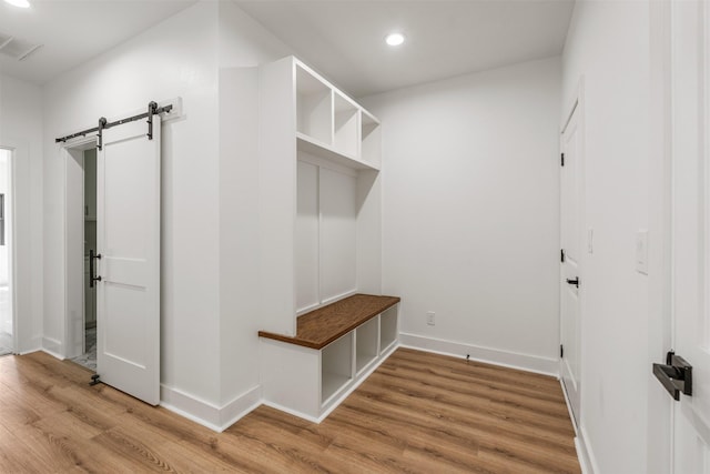 mudroom featuring baseboards, visible vents, light wood finished floors, recessed lighting, and a barn door