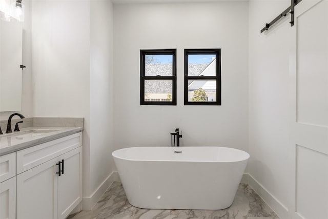 bathroom with baseboards, a soaking tub, marble finish floor, and vanity