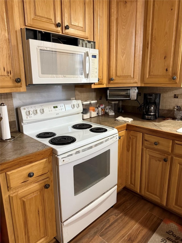 kitchen with tasteful backsplash, white appliances, tile countertops, and dark wood-style floors