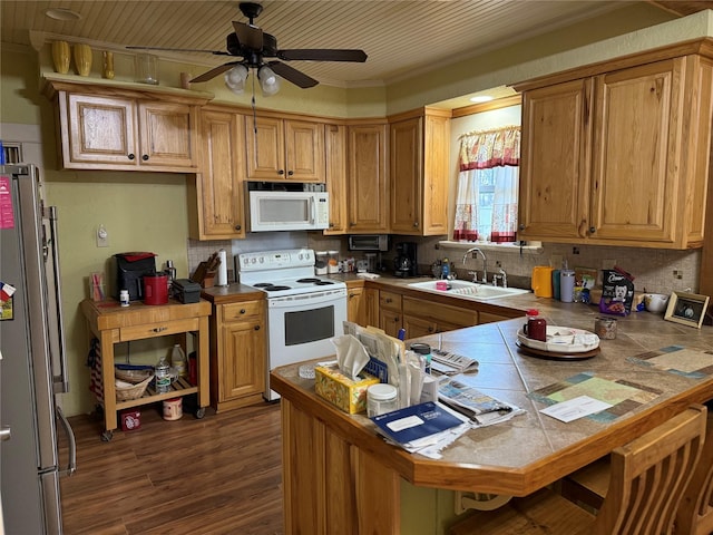 kitchen featuring tasteful backsplash, white appliances, a sink, and a peninsula