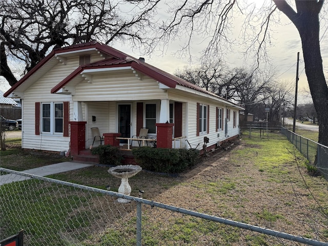 view of front of house featuring a porch, fence private yard, metal roof, and a front lawn