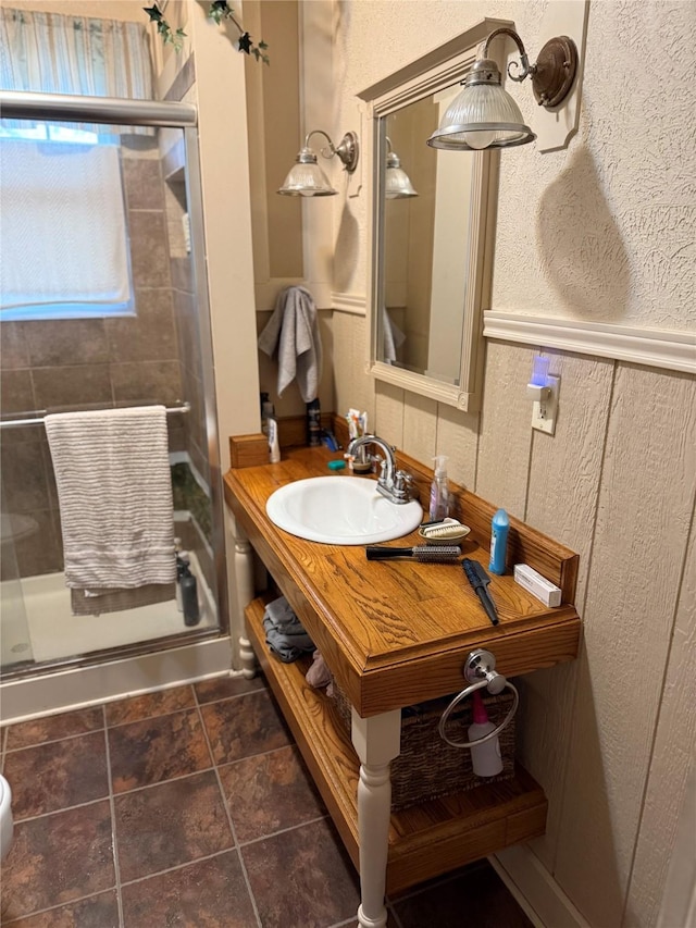 bathroom with a shower stall, vanity, and a textured wall