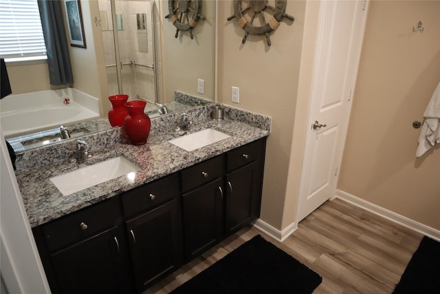 full bath with wood finished floors, a sink, baseboards, and double vanity