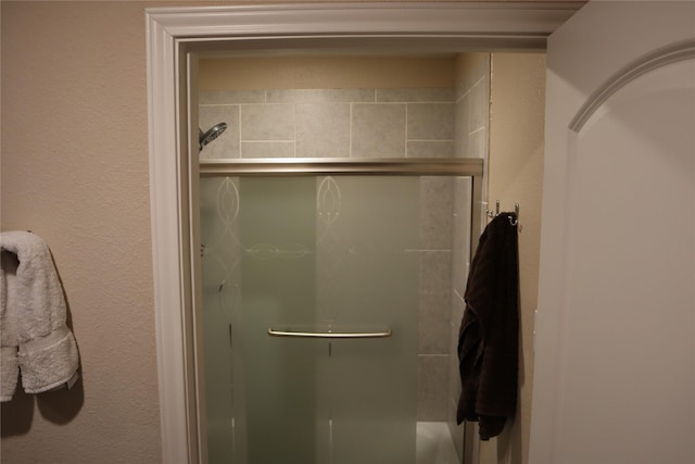 bathroom with a shower stall and a textured wall