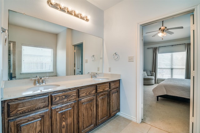 ensuite bathroom with double vanity, a ceiling fan, a sink, tile patterned flooring, and baseboards