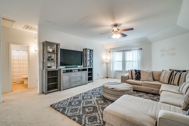 living room with light carpet, visible vents, attic access, and a ceiling fan