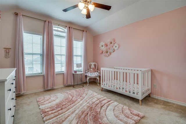 carpeted bedroom with a nursery area, baseboards, vaulted ceiling, and a ceiling fan