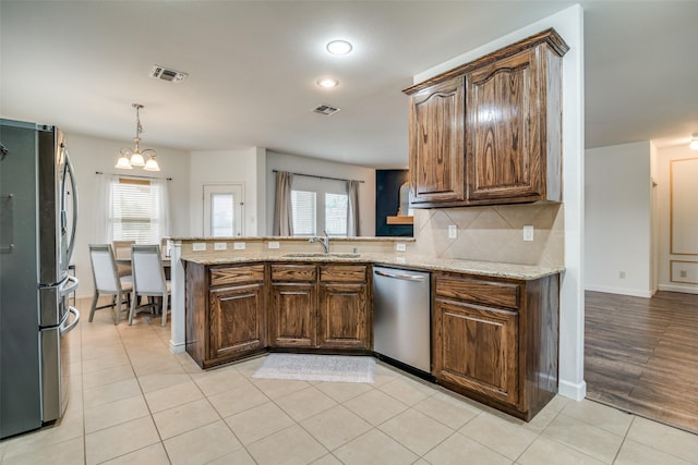 kitchen with stainless steel appliances, a peninsula, backsplash, and a healthy amount of sunlight