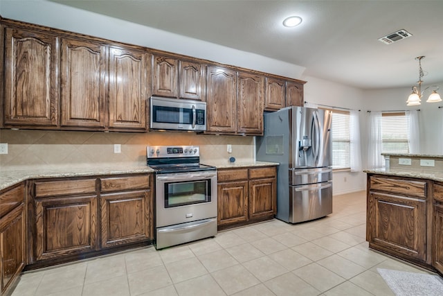 kitchen with pendant lighting, stainless steel appliances, visible vents, decorative backsplash, and light stone countertops