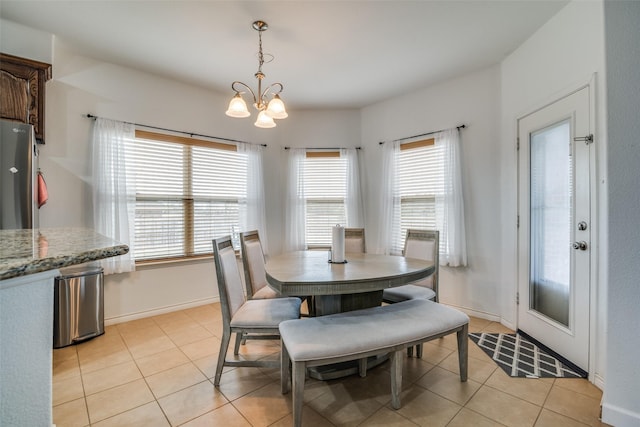 dining space featuring light tile patterned floors, baseboards, and a notable chandelier