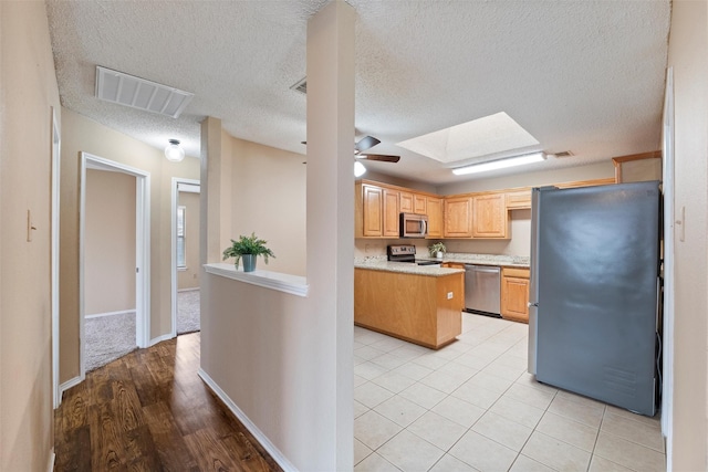 kitchen with ceiling fan, a skylight, visible vents, light countertops, and appliances with stainless steel finishes