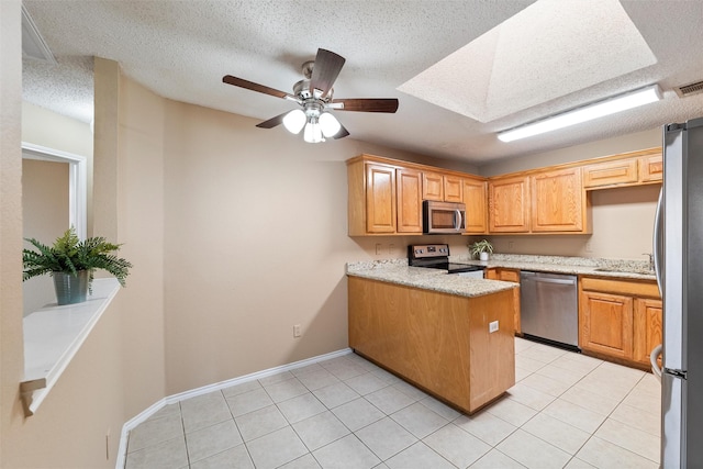 kitchen featuring light tile patterned floors, appliances with stainless steel finishes, a peninsula, a textured ceiling, and a sink