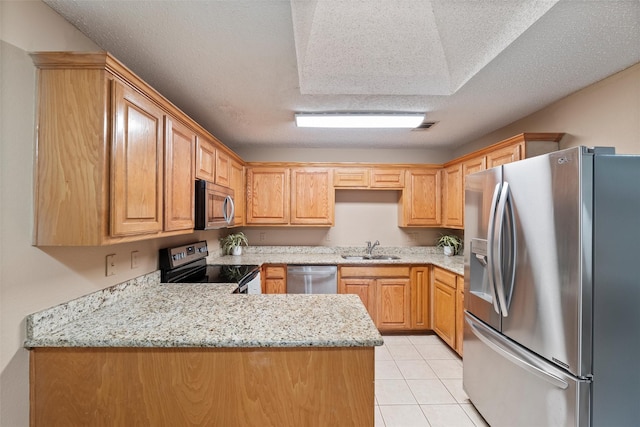 kitchen with light tile patterned floors, a peninsula, a sink, visible vents, and appliances with stainless steel finishes