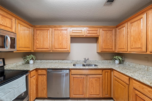 kitchen with visible vents, appliances with stainless steel finishes, light stone countertops, a textured ceiling, and a sink