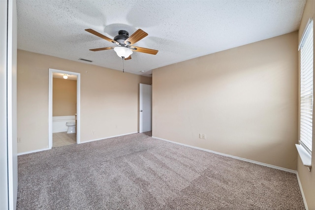 unfurnished bedroom with a textured ceiling, carpet floors, multiple windows, and visible vents