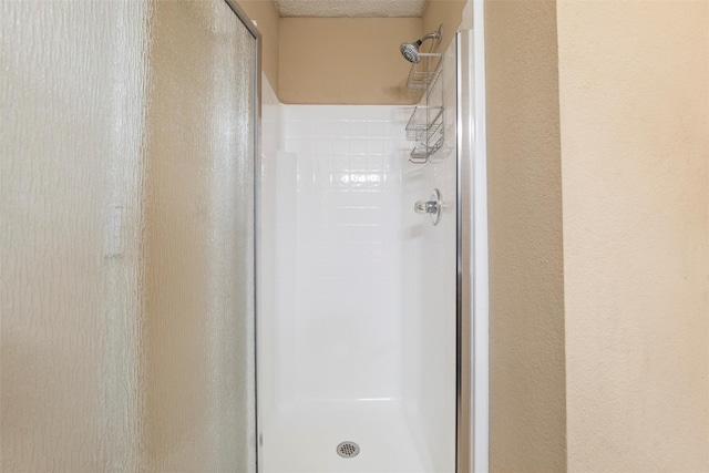 bathroom with a shower stall and a textured ceiling