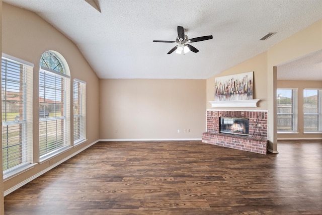 unfurnished living room featuring dark wood-style flooring, a fireplace, visible vents, vaulted ceiling, and plenty of natural light