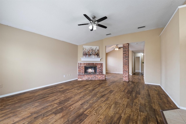 unfurnished living room featuring lofted ceiling, a brick fireplace, visible vents, and wood finished floors